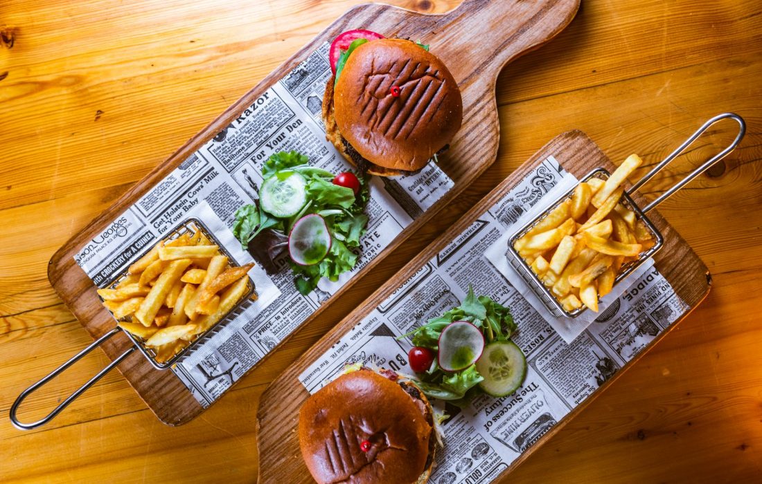Two burgers with French fries and a side salad served on a wooden slate at the Trattoria AD 1530 in Mdina, the ancient city of Malta.